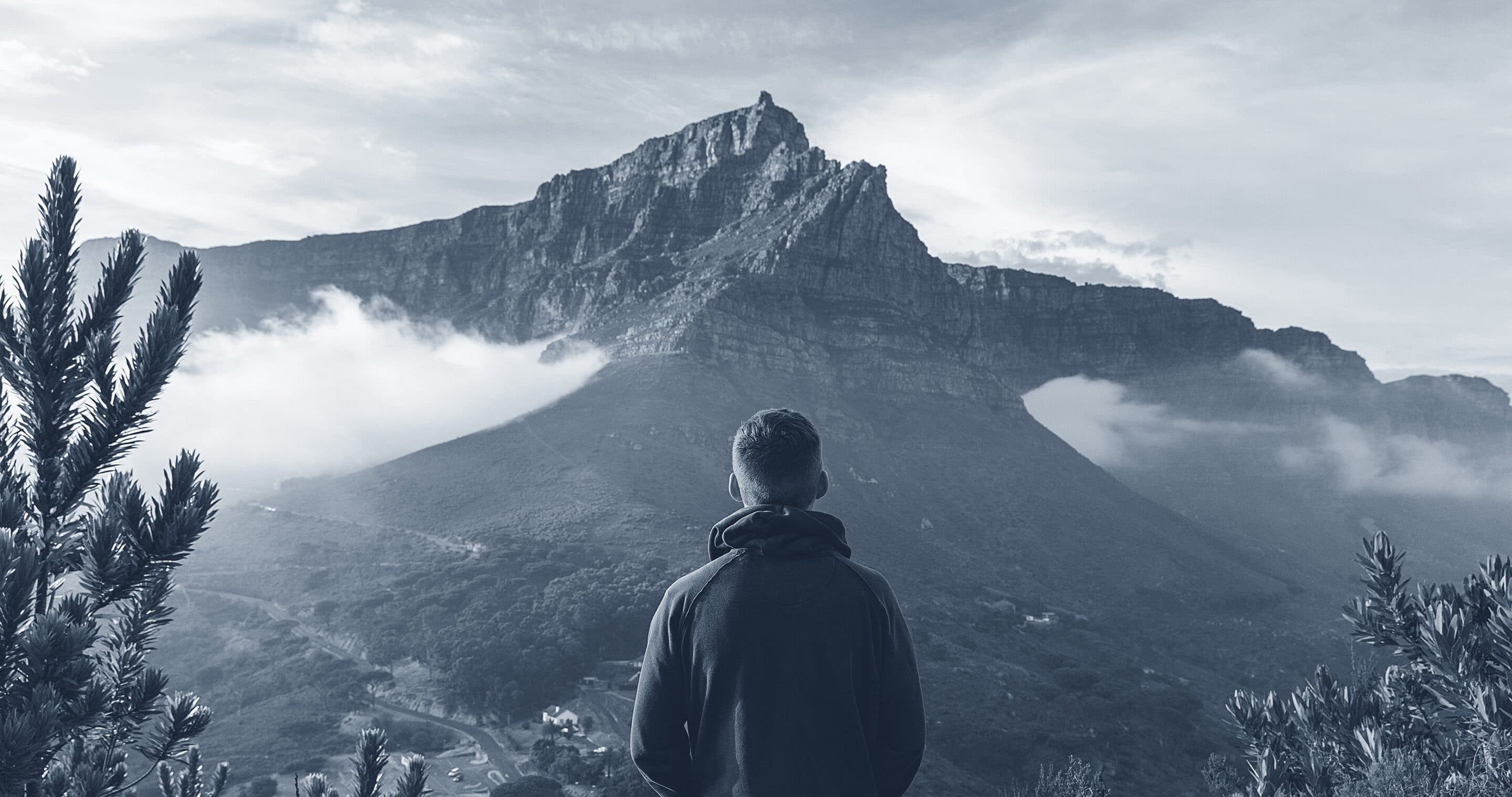 A hiker standing on a ridge at first light, looking across a range of mountains