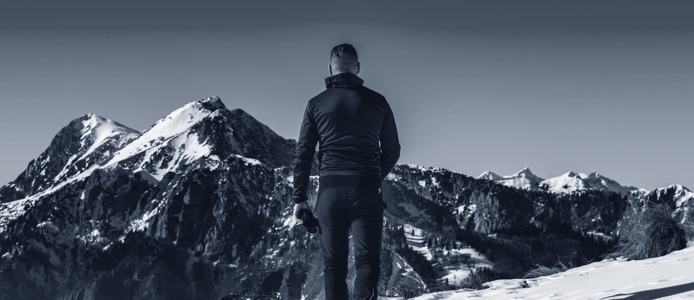 A climber ascending a snow-covered mountain ridge under a clear blue sky